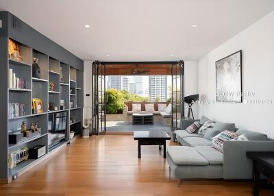 Spacious living room with modern decor and large window opening to outdoor patio.