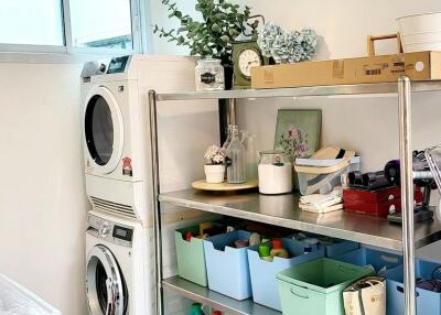 Laundry room with stacked washer dryer and shelving units