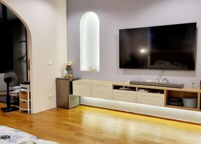Modern bedroom with hardwood floors, wall-mounted TV, and built-in storage