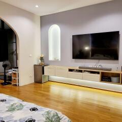 Modern bedroom with hardwood floors, wall-mounted TV, and built-in storage