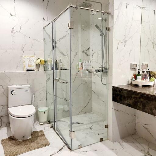 Modern bathroom with glass shower enclosure and marble walls