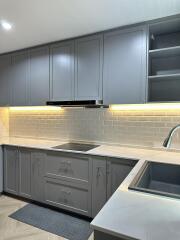 Contemporary kitchen with grey cabinets, white countertop, and stainless steel sink