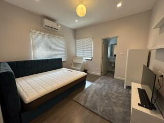 Bedroom with bed, wall-mounted air conditioner, TV, and attached bathroom