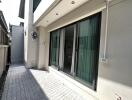 Outdoor view of a modern building exterior with sliding glass doors and a small paved patio area