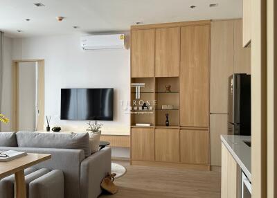 Modern living room with a sofa, TV, air conditioner, wooden cabinets, and a dining table