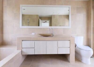 Modern bathroom with large mirror, sink, toilet, and bathtub