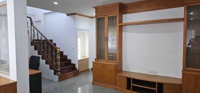 Spacious living room with built-in wooden shelves and staircase