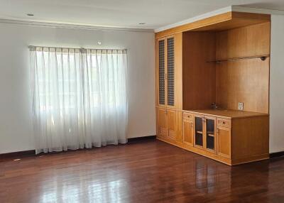 Spacious living room with large window and built-in wooden cabinetry