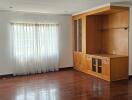 Spacious living room with large window and built-in wooden cabinetry