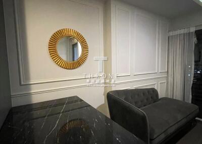 Modern living room with a black marble table, a gray couch, and a circular decorative mirror