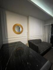 Modern living room with a black marble table, a gray couch, and a circular decorative mirror