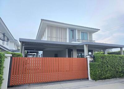 Modern two-story house with a red wooden gate and green hedges