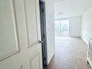 Empty white hallway with open door and view of balcony