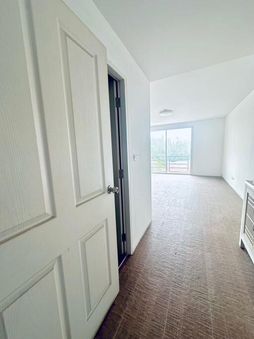 Empty white hallway with open door and view of balcony
