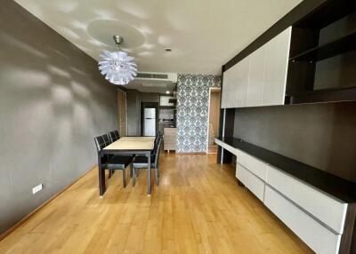 Modern dining area with adjacent kitchen featuring wooden flooring, contemporary furniture, and patterned accent wall