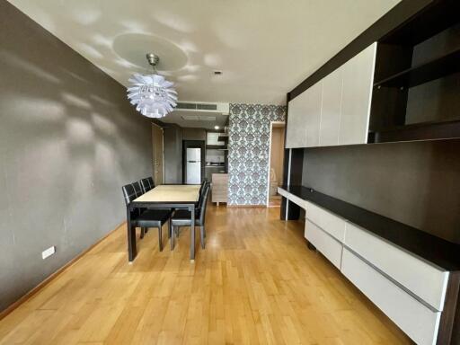 Modern dining area with adjacent kitchen featuring wooden flooring, contemporary furniture, and patterned accent wall