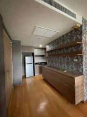 Compact kitchen with a modern fridge, wooden flooring, wall-mounted open shelves, and built-in cabinets.