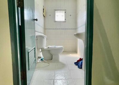 Bathroom with white ceramic tiles, toilet, and sink