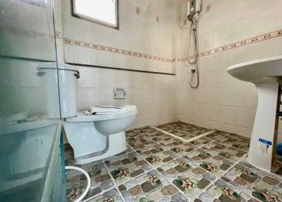 Clean bathroom with tiled floors and walls, featuring a toilet, sink, and shower.