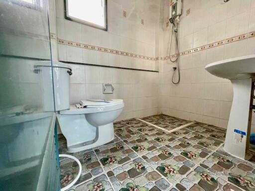 Clean bathroom with tiled floors and walls, featuring a toilet, sink, and shower.