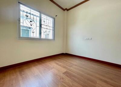 Spacious empty bedroom with wooden flooring and a window