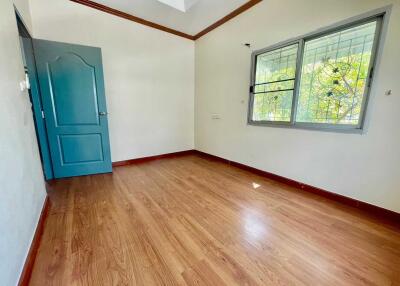 Empty bedroom with wooden floor and a blue door