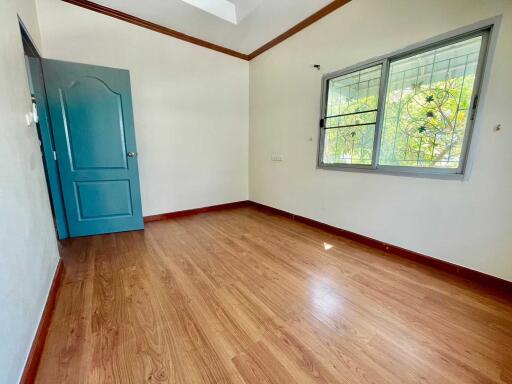 Empty bedroom with wooden floor and a blue door