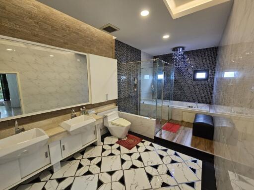 Modern bathroom with dual sinks, large mirror, glass-enclosed shower, and bathtub