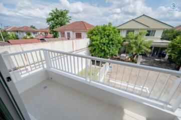 A balcony with railing overlooking a neighborhood with houses and trees