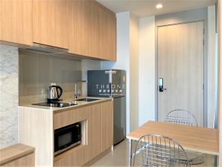 Modern kitchen with wooden cabinets, stainless steel appliances, and a small dining area