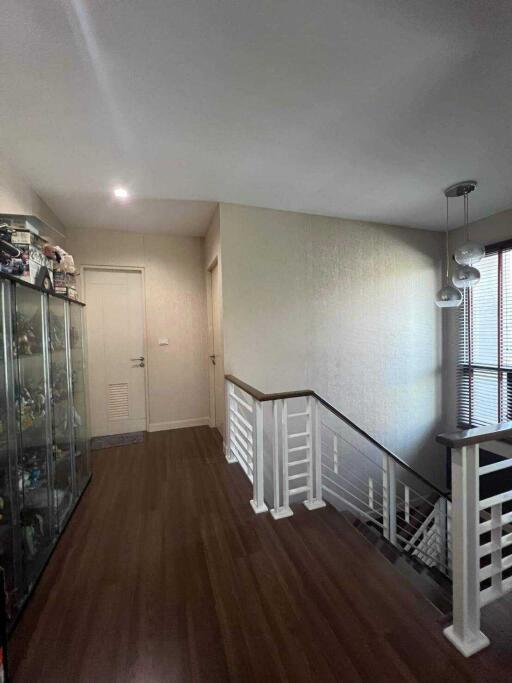 A hallway with wooden flooring, a stair railing, and decorative elements.