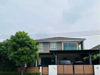 Two-story house with a balcony, garage, and surrounding greenery