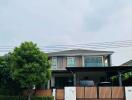 Two-story house with a balcony, garage, and surrounding greenery