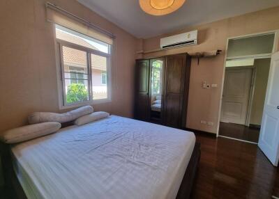 Bedroom with a large bed, window, wardrobe, and air conditioning unit