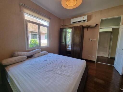 Bedroom with a large bed, window, wardrobe, and air conditioning unit