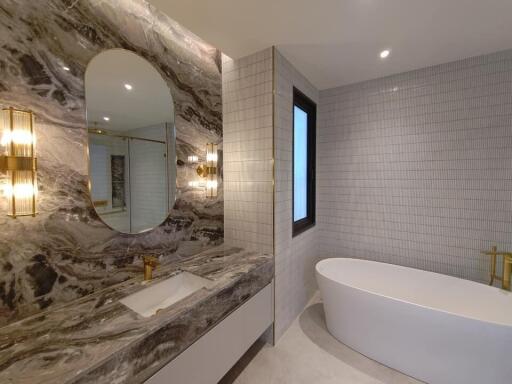 Modern bathroom with marble wall, oval bathtub, and elegant lighting