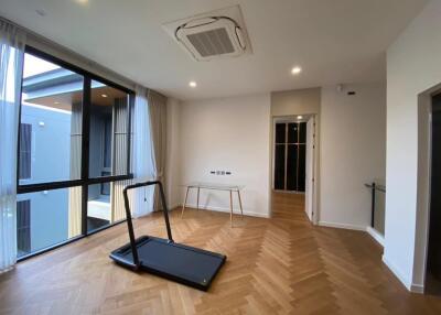 Room with large window, wooden floor, treadmill, and desk