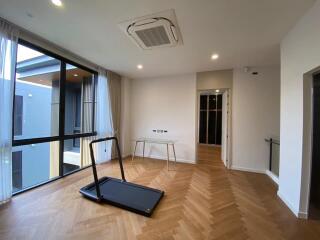 Room with large window, wooden floor, treadmill, and desk