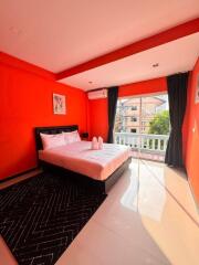 Bright bedroom with red walls and a large bed near a window