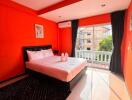 Bright bedroom with red walls and a large bed near a window