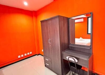 Simple bedroom with bright orange walls and basic furniture