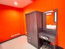 Simple bedroom with bright orange walls and basic furniture