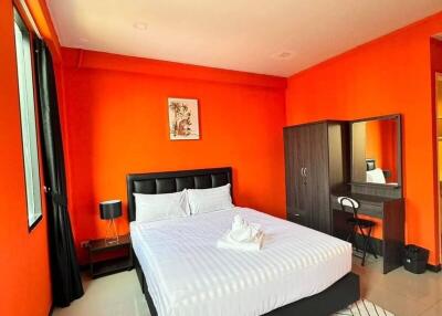 Bright bedroom with orange walls, bed, wardrobe, and desk