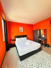 Bright bedroom with orange walls, bed, wardrobe, and desk