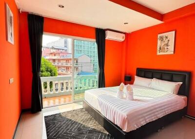 Modern bedroom with vibrant orange walls, a large bed, and a balcony view