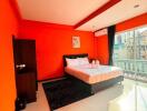 Bright and spacious bedroom with orange walls and large window