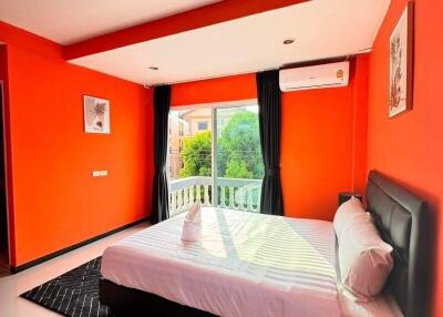 Bright bedroom with orange walls, large windows, and a bed