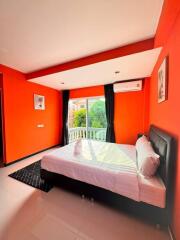 Bright bedroom with orange walls, large windows, and a bed