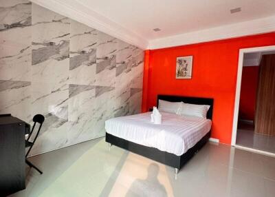 Modern bedroom with marble accent wall and bright orange feature wall