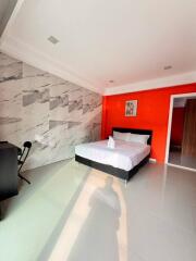 Modern bedroom with marble accent wall and bright orange feature wall